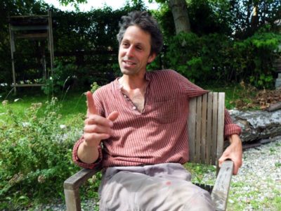 Holzbildhauer und „Anders-Herum Denken-Künstler“ Johannes Volkmann unterm Walnussbaum in Riegsee.