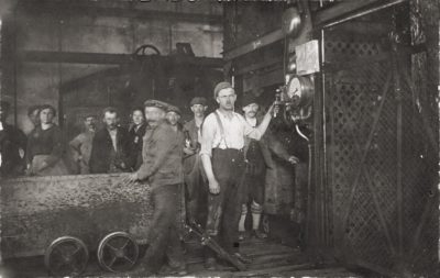 Bergleute um 1900 vor der Einfahrt in die Grube. In der Bildmitte steht der Anschläger, dessen Aufgabe war es, die Signalanlage zur Verständigung mit dem Maschinisten des F ö rderantriebes zu bedienen. Eine Ausrüstung, wi e Helme oder Schützer, gab es so gut wie gar nicht, erst nach dem Zweiten Weltkrieg wurde diese verpflichtend eingeführt.